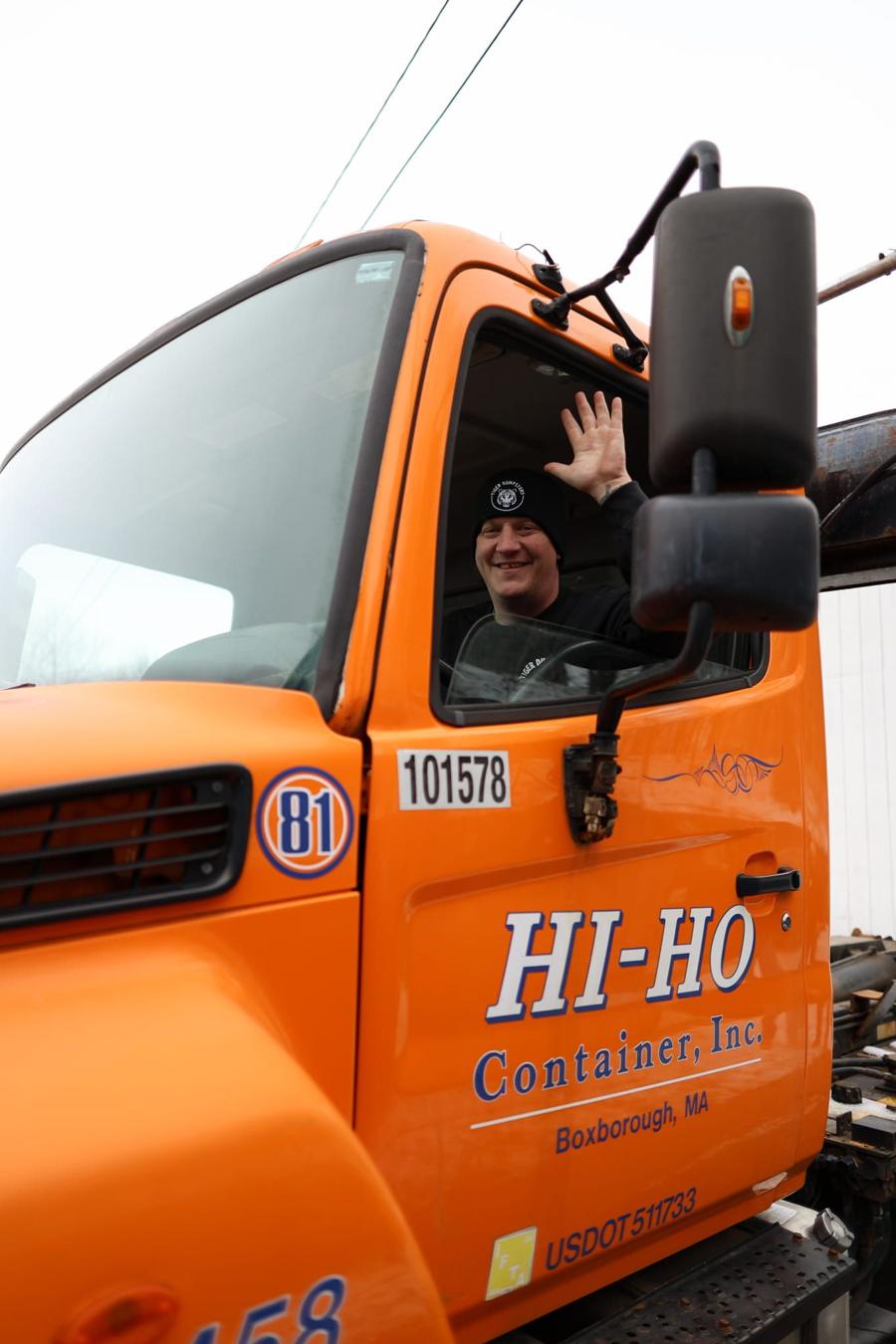 Tiger driver waving from an orange roll-off truck